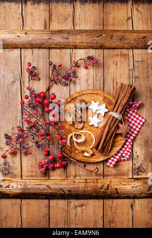 Xmas Cookies, Walnüssen, getrockneten Orangenschalen, Zimtstangen und Zweig mit roten Beeren auf Holz Textur Hintergrund Stockfoto