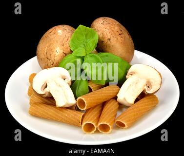 Baby Bella Pilze, Pasta und Basilikum auf einem schwarzen Hintergrund. Stockfoto