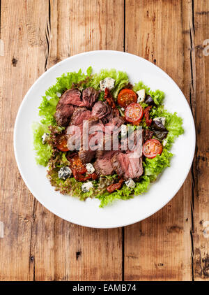 Salatblätter mit Scheiben Roastbeef und sonnengetrockneten Tomaten auf hölzernen Hintergrund Stockfoto