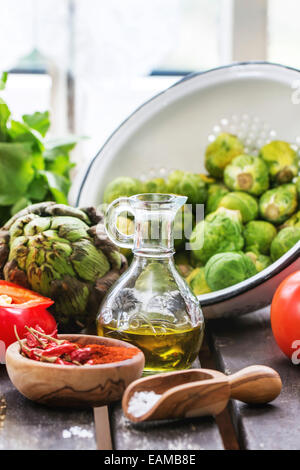 Variation von frischem Gemüse Tomaten, Pfeffer, Paprika, Artischocken und Brüssel Sprossen auf alten Tisch in der Nähe von Fenster im Tageslicht. Stockfoto