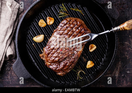 Gegrillten Ribeye Steak und Fleisch Gabel auf Grillpfanne auf dunklem Hintergrund Stockfoto