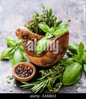 Frische würzige Kräuter aus Olivenholz Mörser auf dunklem Hintergrund Stockfoto