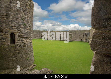 Zwischen antiken Steintürme des Inneren des historischen Beaumaris Castle mit riesigen Mauern & grasigen Innenhof unter blauem Himmel anzeigen Stockfoto