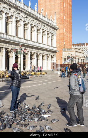 Menschen, die Tauben füttern, im St. Marks Platz, Venedig, Italien Stockfoto