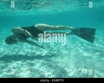 Weibliche Schwimmer tragen, Maske und Flossen Tauchen ruhig unter Wasser im Ozean über sandigen Boden Stockfoto