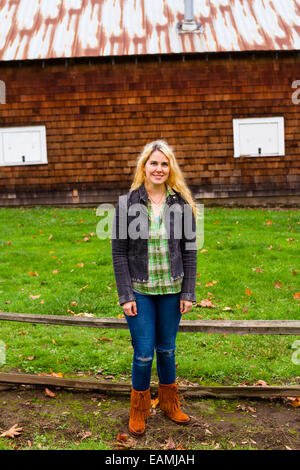 Lifestyle Porträt einer Frau, die draußen mit einer Scheune im Hintergrund. Stockfoto