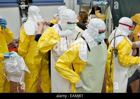 Würzburg, Deutschland. 3. November 2014. Teilnehmer einer Ebola-Training Kurs Hilfe setzen einander auf ihre Schutzkleidung während der Vorbereitungen für die Arbeit in Krisengebieten in Würzburg, Deutschland, 3. November 2014. Würzburg hat das einzige Ebola-Training-Center außerhalb der Bundeswehr. Diese Menschen werden ausgebildet, Arbeit in deutschen Isolierung Stationen zu helfen, die Ebola-Krise unter Kontrolle zu bringen. Foto: DANIEL KARMANN/Dpa/Alamy Live News Stockfoto