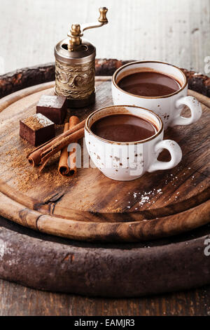 Heißer Schokolade bestreut mit weißer Schokolade und Gewürzen auf dunklem Holz Stockfoto