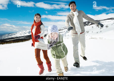 Eine Familie mit drei laufen im Schnee Stockfoto