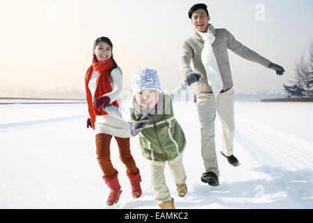 Eine Familie mit drei laufen im Schnee Stockfoto