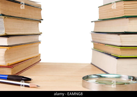 Kugelschreiber, Bleistift, Haufen von alten Büchern und Lupe isoliert auf weiss Stockfoto