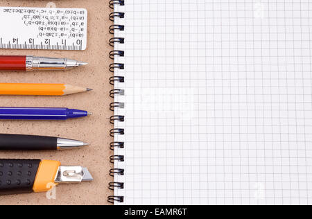 Kugelschreiber, Bleistift und Papier Messer mit geprüften Notebook auf Holzstruktur Stockfoto