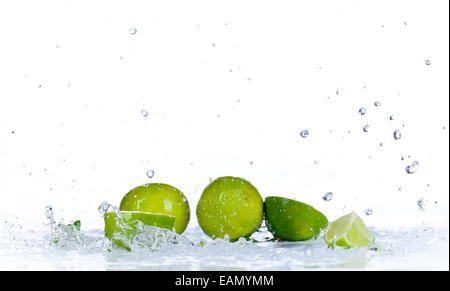 Frische Limetten mit Spritzwasser isoliert auf weißem Hintergrund Stockfoto