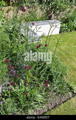 L-Beton Sitzbank mit Schiefer oben im Garten mit Blumen, London Stockfoto