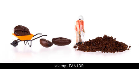 Miniatur-Arbeiter mit Powerdrill arbeitet an einer Kaffeebohne Stockfoto