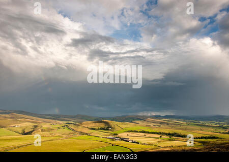 Großen dramatischen Himmel über einer Landschaft des Peak District in der Nähe von Glossop. Regenwolken in der Ferne mit Sonnenlicht auf die Landschaft. Stockfoto