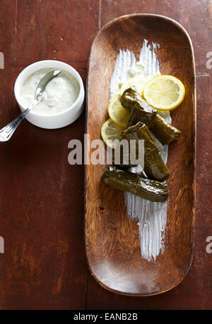 Sarma Dolma Weinblätter mit Joghurt und Zitronensaft in eine hölzerne Schüssel auf einem antiken Holztisch Stockfoto