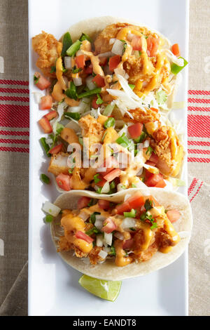 Shrimp Tacos auf einem weißen Teller mit Kalk und roten Streifen Serviette Stockfoto