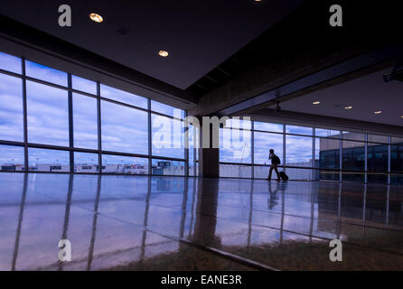 Mann zu Fuß & reden über Handy am Flughafen Stockfoto