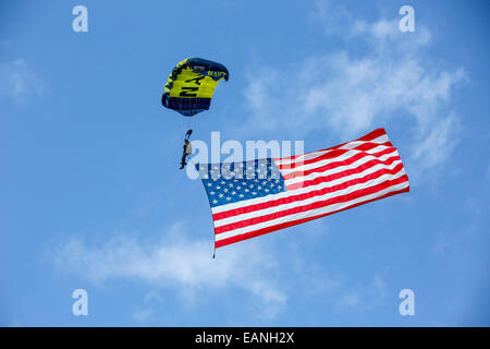 Mitglied der US-Navy Fallschirm-Team, die Frösche springen, fliegt die amerikanische Flagge, als er bereitet sich auf die Demonstration Grou landen Stockfoto