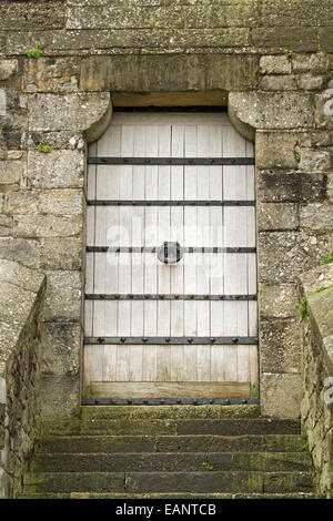 Große weiße gemalte hölzerne Tür an Spitze der alten Steintreppen & in dicken Steinmauern von Caernarfon Castle, Wales Stockfoto