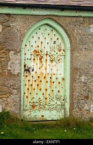 Alte Tür mit verwitterten grüne Farbe & riesige dekorative Scharniere in der historischen St. Tudno Church Great Orme, Llandudno, Wales Stockfoto