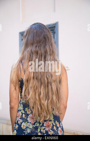 Rückansicht einer jungen Frau mit langen braunen Haaren stehen im freien Stockfoto