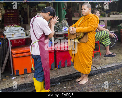 Bangkok, Bangkok, Thailand. 19. November 2014. Ein Markt-Verkäufer betet mit einem buddhistischen Mönch und Almosen zu Verdienst in Khlong Toei Markt in Bangkok zu bilden. Zwischen Juli und September die Wirtschaft 0,6 Prozent im Vergleich zum Vorjahr wuchs, berichtet des National Economic and Social Development Board (NESDB). Thailands Wirtschaft erreicht ein schwache 0,2 Prozent Wachstum in den ersten neun Monaten des Jahres. Die NESDB sagte, dass die thailändische Wirtschaft wird voraussichtlich um 1 Prozent im Jahr 2014 wachsen. Behörden sagen, dass die träge wächst, weil Touristen nach Thailand im Zuge des Staatsstreichs in Ma nicht zurückgekehrt sind Stockfoto