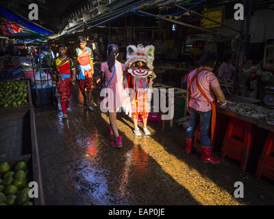 Bangkok, Bangkok, Thailand. 19. November 2014. Chinesische Löwen Tänzer gehen einer Gasse zwischen Marktständen in Khlong Toei Markt in Bangkok. Zwischen Juli und September die Wirtschaft 0,6 Prozent im Vergleich zum Vorjahr wuchs, berichtet des National Economic and Social Development Board (NESDB). Thailands Wirtschaft erreicht ein schwache 0,2 Prozent Wachstum in den ersten neun Monaten des Jahres. Die NESDB sagte, dass die thailändische Wirtschaft wird voraussichtlich um 1 Prozent im Jahr 2014 wachsen. Behörden sagen, dass das schleppende Wachstum ist, weil Touristen nach Thailand im Zuge des Putsches im Mai 2014 und th nicht zurückgegeben haben Stockfoto