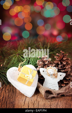 Weihnachtsgeschenk in Kästchen, dekoriert mit irdenen Herz, Zapfen und Zweige. Bunte unscharfen Lichter im Hintergrund Stockfoto
