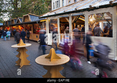 Weihnachtseinkäufer in Manchester UK, festlich dekorierte Holzchalets in St Annes Square. Geschäftiges Stadtzentrum Weihnachtsgeschäfte, Stände & Markthändler. Stockfoto