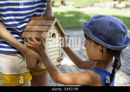 Junges Mädchen einen Hut Sommer Kleid und Sonne, hält ein Vogelhaus. Stockfoto