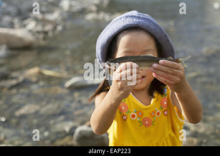 Junges Mädchen mit einem Sommerhut, der einen Fisch hält. Stockfoto