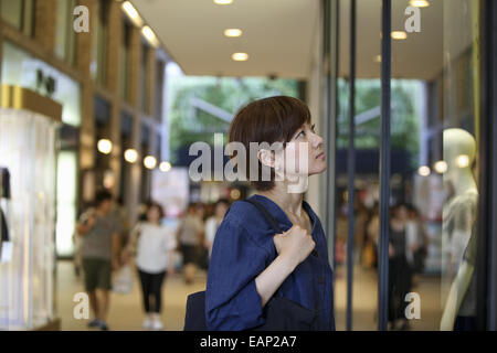 Eine Frau in einem Einkaufszentrum, einem Shop Schaufenster betrachten. Stockfoto
