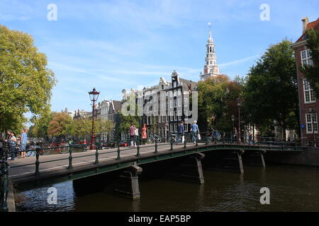 Alte Brücke am Kloveniersburgwal Kanal zwischen Raamgracht und Rußland in Amsterdam, mit Turm des 17. Jahrhunderts Zuiderkerk Kirche Stockfoto