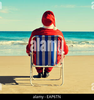Weihnachtsmann sitzt im Strandkorb am Strand Stockfoto
