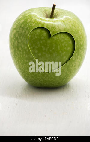 Grüner Apfel mit geschnitzten Herz, konzeptionelle Gesundheit und wellness Stockfoto