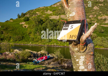 Ein Kajak-OL Marker auf einer Insel mit einem Dauerkatheter Kajak auf Ullswater im Lake District, UK. Stockfoto