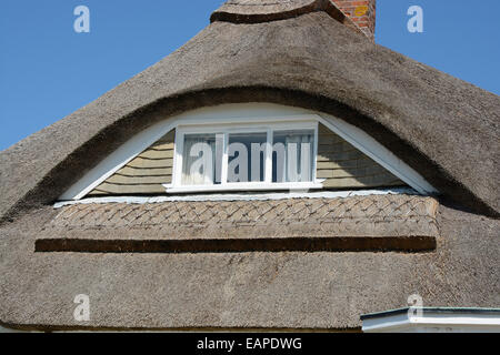 Augenbraue Stilfenster festgelegt in einem Strohdach auf Hütte in Sussex. England Stockfoto
