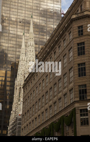 Die Trwin Türme der St. Patricks Kathedrale zeichnen sich inmitten der eklektischen Architektur entlang der 5th Avenue in New York City. Stockfoto