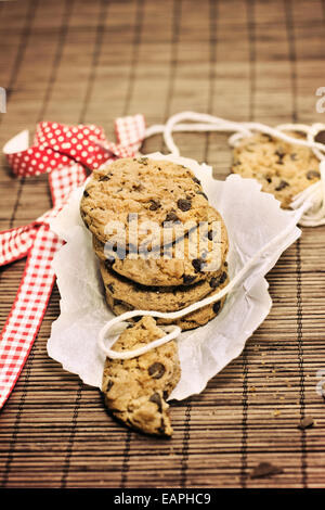 Cookies, Stücke Schokolade auf Bambus Tischdecke rustikal, rote Schleife Stockfoto
