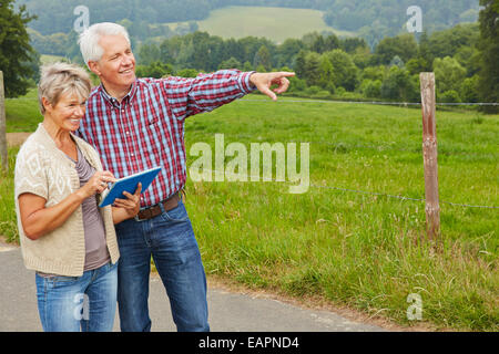 Gerne älteres Paar auf der Suche nach dem Weg mit Tablet-PC beim Wandern Stockfoto