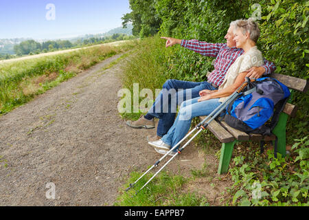 Älteres paar Ziel in der Ferne suchen, beim Sitzen auf einer Bank Stockfoto