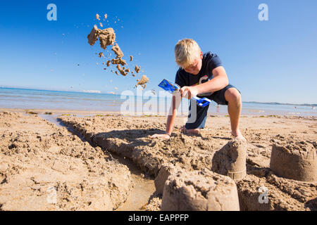 Ein Junge, bauen eine Sandburg am Strand von Bamburgh, Northumberland, UK. Stockfoto