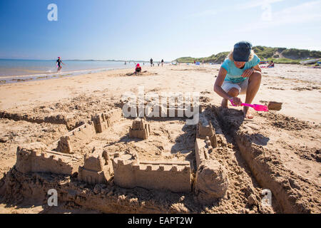 Eine Frau bauen eine Sandburg am Strand von Bamburgh, Northumberland, UK. Stockfoto