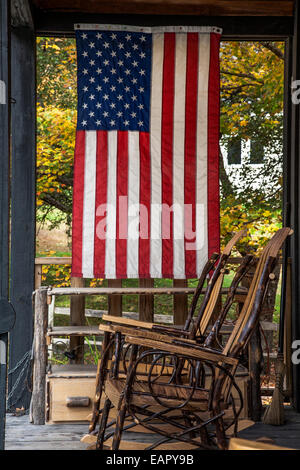 Am 4. Juli amerikanische Flagge auf einer Veranda des Geschenkeladens mit 2 Schaukelstühlen in Vermont, US-Flagge Amerika, Neuengland-Herbststühle, Amerikaner Stockfoto