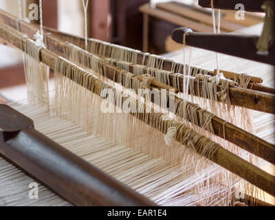 Weberei Webstuhl Detail. Die Komplexität der einen Webstuhl. Weiße Fäden sind über vier verschiedene Arme drapiert. Stockfoto