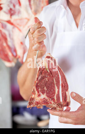 Metzger Holding rohes Fleisch mit Haken Stockfoto