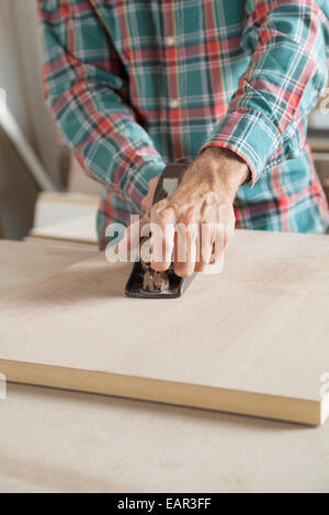 Männlichen Carpenter mit Hobel auf Holzbrett Stockfoto