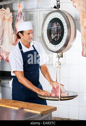 Metzger mit einem Gewicht von Fleisch auf der Skala Stockfoto